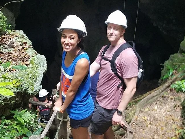 Mann und Frau mit Schutzhelmen stehen auf einem Weg nahe einer Höhle.