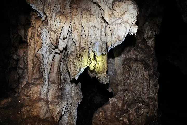 Vista de cerca de estalactitas y estalagmitas dentro de una cueva oscura.